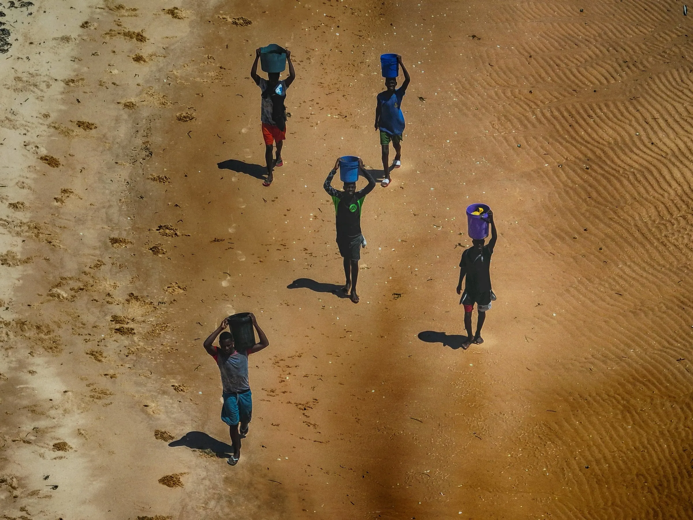 Aerial view of fishers carrying the day’s catch across the sand flats