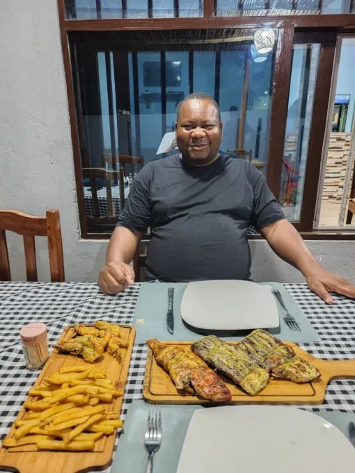 Isac serves freshly grilled fish and chips at Residencial Duma